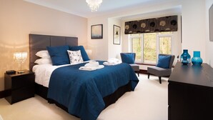 A bedroom with a large bed, bedside tables, a chair, and a desk. - Beech View (Ambleside)