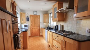 A modern kitchen with wooden cabinets, a gas stove, and a microwave. - Silver Birches (Windermere)