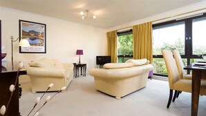 A modern living room with a sofa, a chair, a TV, and a window with curtains. - Mount Sol (Ambleside)