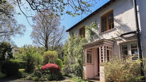 Um edifício com entrada para um jardim, varanda coberta e caminho de cascalho.