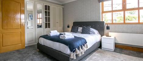 Un dormitorio con cama, mesita de noche, armario y ventana.