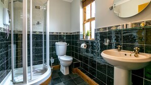 A bathroom with a glass-enclosed shower, a toilet, and a sink with a mirror above it.