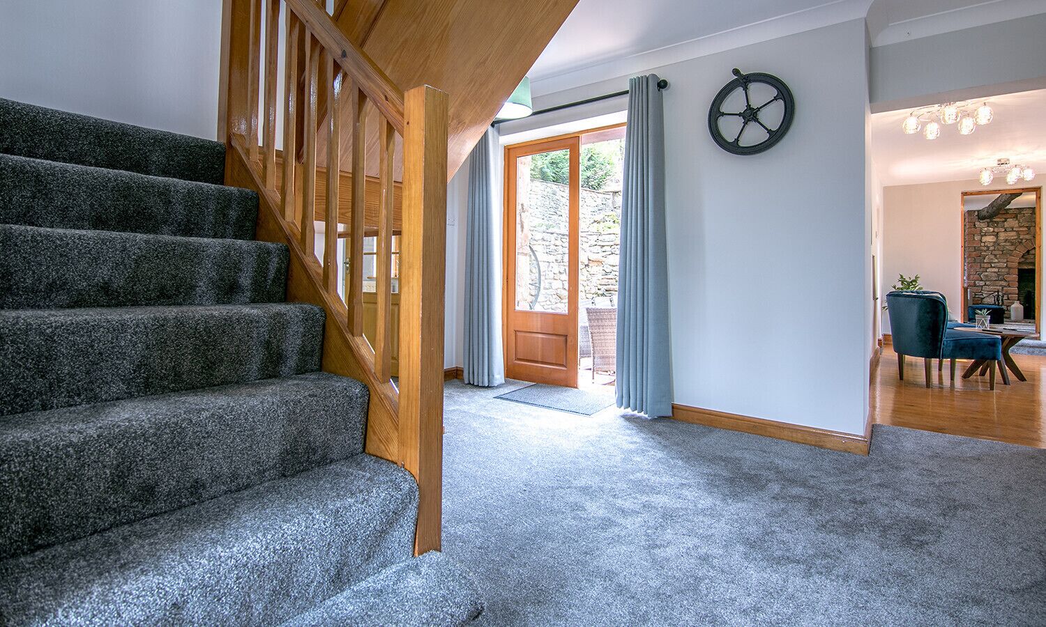 A staircase leading to a door, a stone wall, and a dining area with chairs and a table.