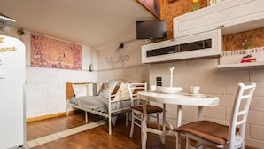 A compact kitchen with a dining area, a bed, and a TV mounted on the wall. - 2417 Dimora Santa Croce by Barbarhouse (Lecce)