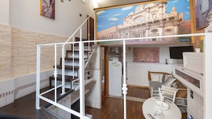 A hotel room with a staircase, a bed with a view, a dining table, and a painting of a historical building. - 2417 Dimora Santa Croce by Barbarhouse (Lecce)