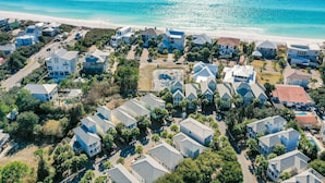 Luchtbeeld van een kustgebied met woningen, een strand en een helder uitzicht op de oceaan.