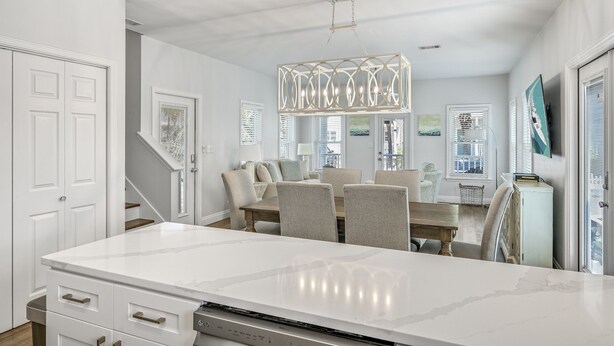 Een moderne keuken met een groot eiland, witte kasten en een hangende lamp.