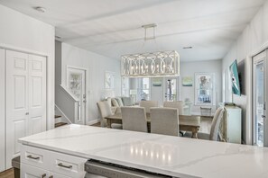 A modern kitchen with a large island, white cabinetry, and a hanging light fixture.