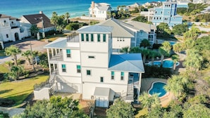 Una casa de diversos pisos amb un gran jardí davanter, una piscina i vistes a l'oceà.
