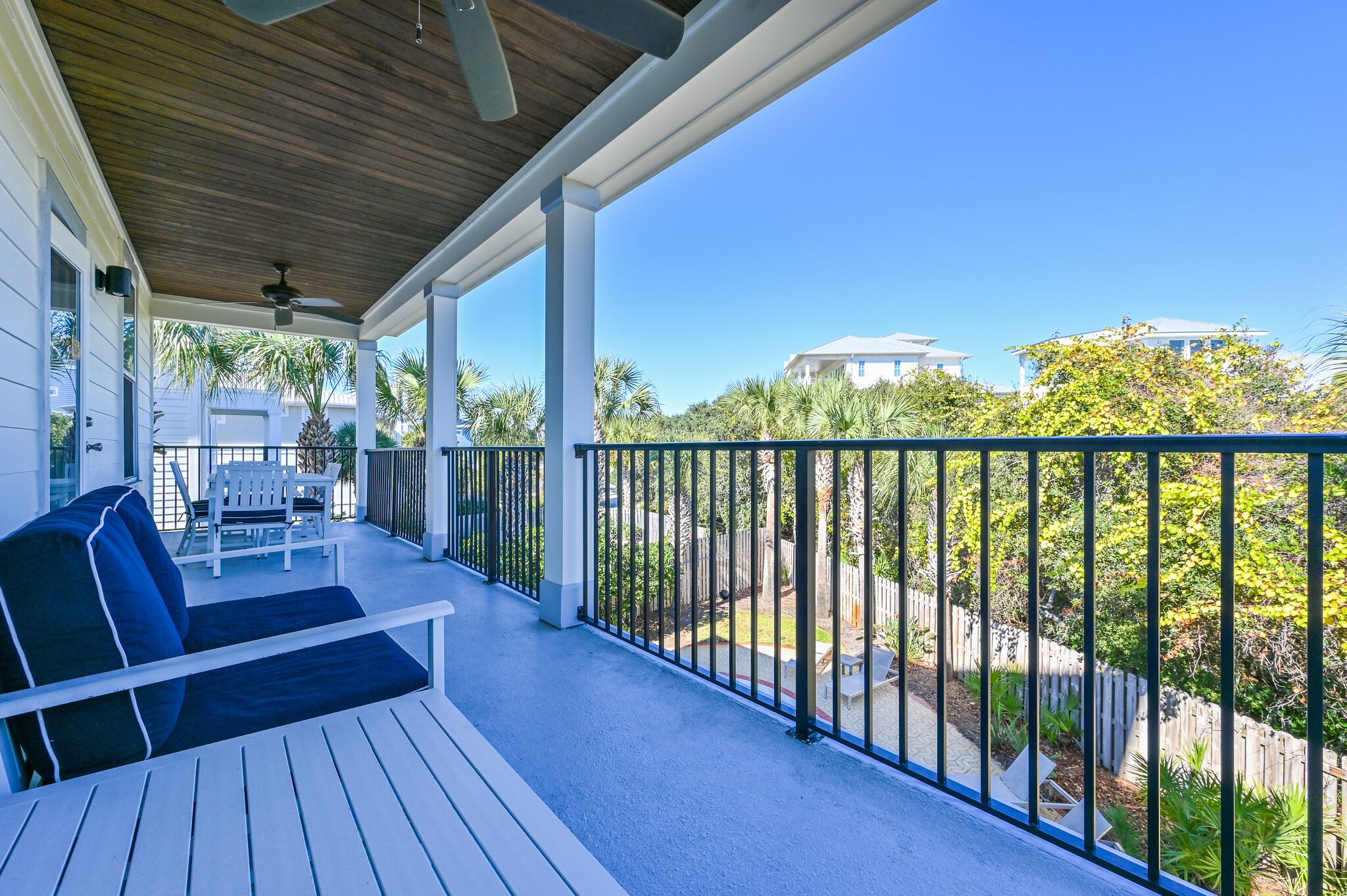 A covered outdoor area with a wooden ceiling, white columns, and a black metal railing.