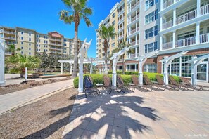 A multi-story hotel with outdoor seating areas, palm trees, and a clear blue sky.