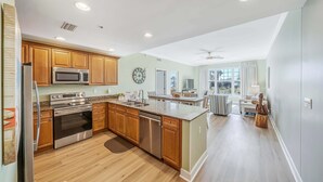 A modern kitchen with wooden cabinets, stainless steel appliances, and a large island. - FREE Daily Golf! Reflections 211 Bayfront Beauty, Heated Resort Pool, Hot Tub (Panama City)