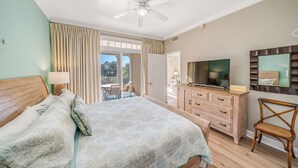 A bedroom with a bed, a wooden dresser, a television, and a chair. - FREE Daily Golf! Reflections 211 Bayfront Beauty, Heated Resort Pool, Hot Tub (Panama City)