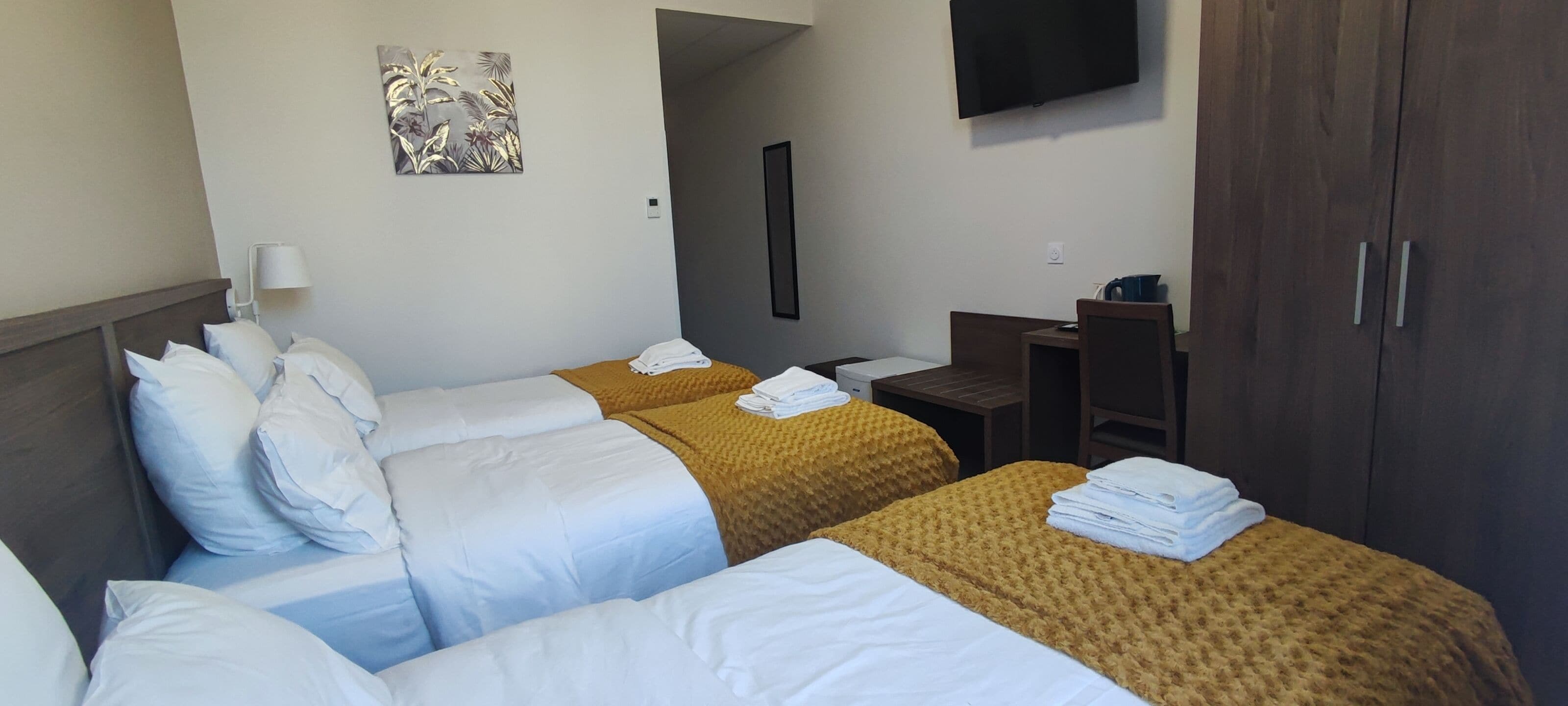 Habitación de hotel con dos camas, un escritorio, un televisor y un armario.