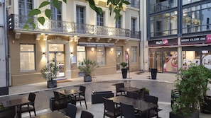 A hotel with outdoor seating and a balcony. - Square Hôtel (Nîmes)