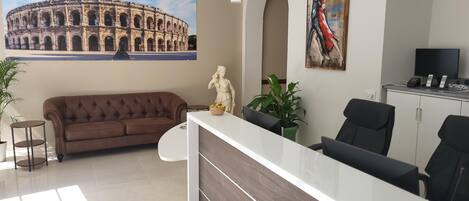 Un área de recepción con un sofá, una estatua, un cuadro, un televisor y un escritorio.
