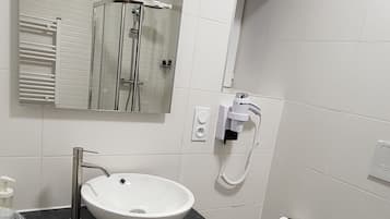Un baño moderno con un lavabo blanco, un espejo, un inodoro y una cabina de ducha.