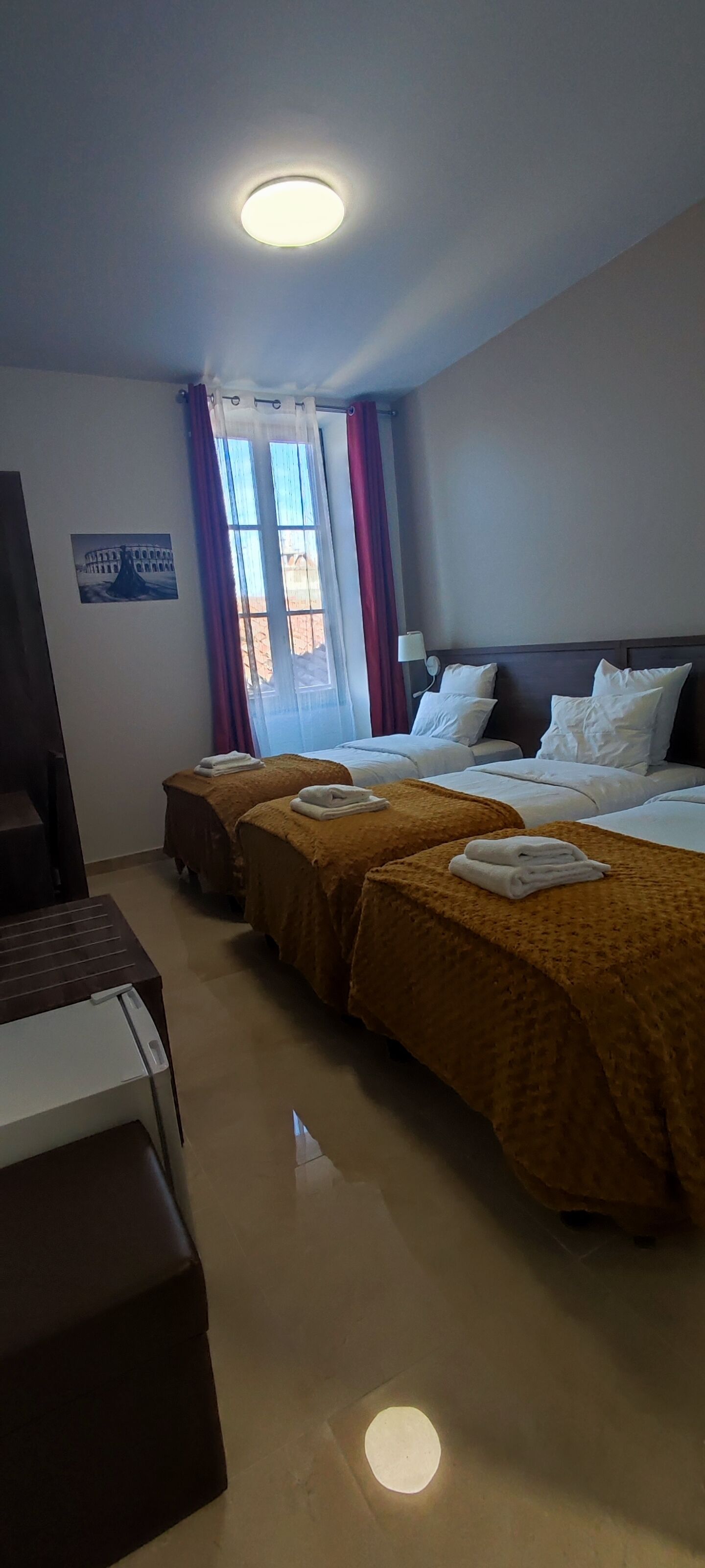 A hotel room with two beds, a desk, a chair, and a window with curtains.