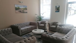 A modern living room with a sectional sofa, armchairs, and a round coffee table. - Square Hôtel (Nîmes)