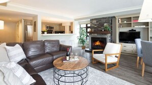 Een moderne woonkamer met een leren bank, een ronde salontafel, een open haard en een televisie.