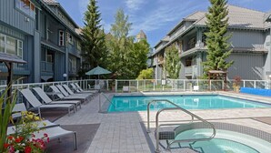 A pool area with lounge chairs, a small hot tub, and a view of surrounding buildings. - MAGNIFICENT SKI-IN/OUT 1BR: AC and Gym (Whistler)