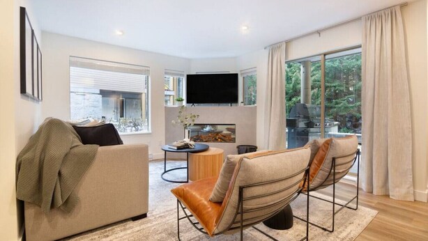 Un salon moderne comprenant un canapé, deux fauteuils, une table basse et un téléviseur à écran plat.