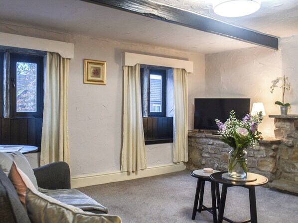 A living room with a stone fireplace, a television, a sofa, and two small tables with a vase of flowers. - 2 bedroom accommodation in Barrowford (Barrowford)