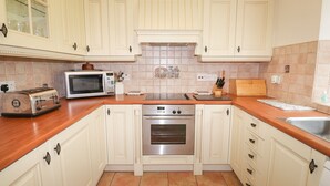 A kitchen with white cabinets, a microwave, a toaster, a stove, and a sink. - Millerbeck (Ambleside)