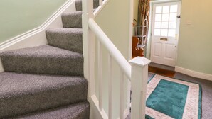A staircase with carpeted steps and white railings leading to a door with a window and a curtain. - Millerbeck (Ambleside)