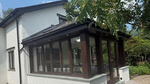 Ett modernt hus med en inglasad veranda, stora fönster och en gång av sten.