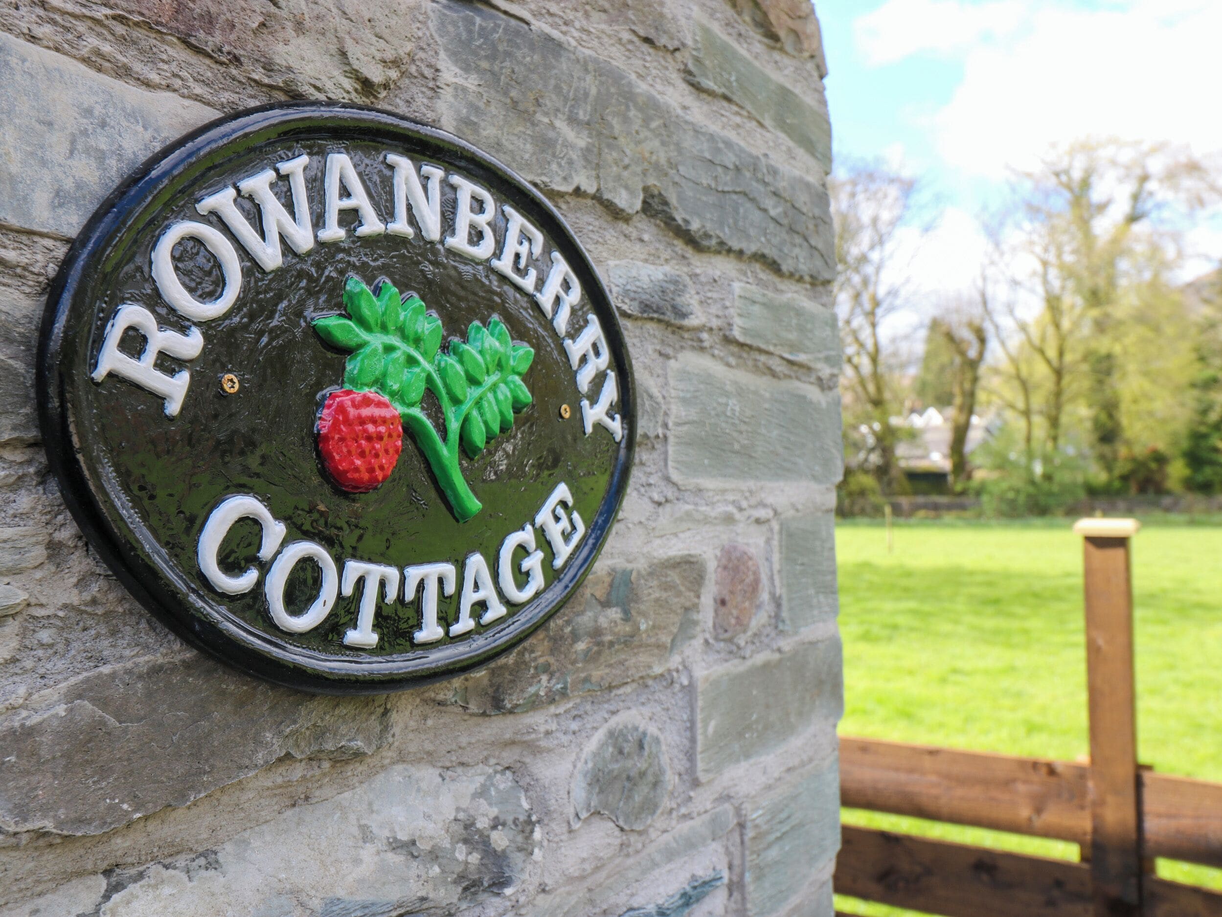 A sign for Rowanberry Cottage with a strawberry and leaf design.
