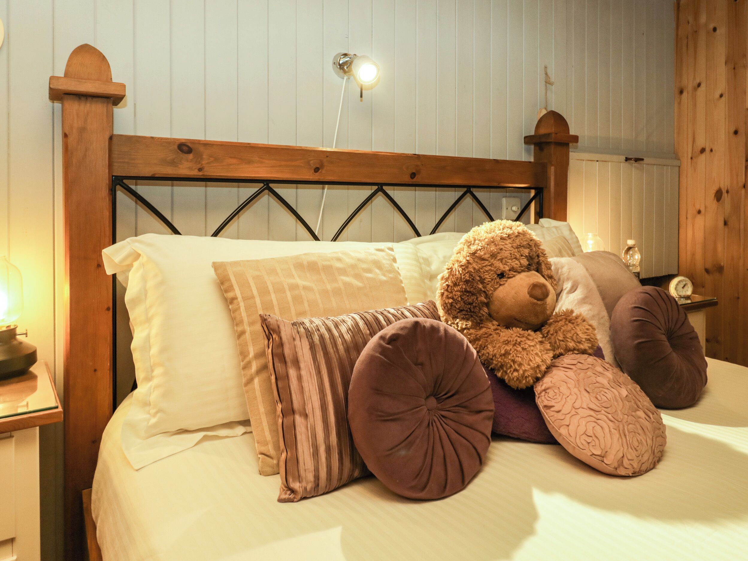 A bed with a wooden headboard, multiple pillows, and a teddy bear.