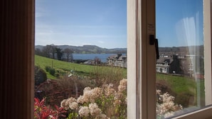 A view through a window of a landscape with a lake, green fields, and houses in the background.