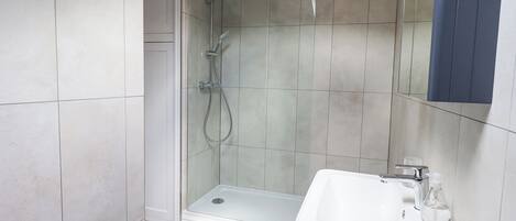 Un baño moderno con ducha de vidrio, lavabo blanco y espejo.