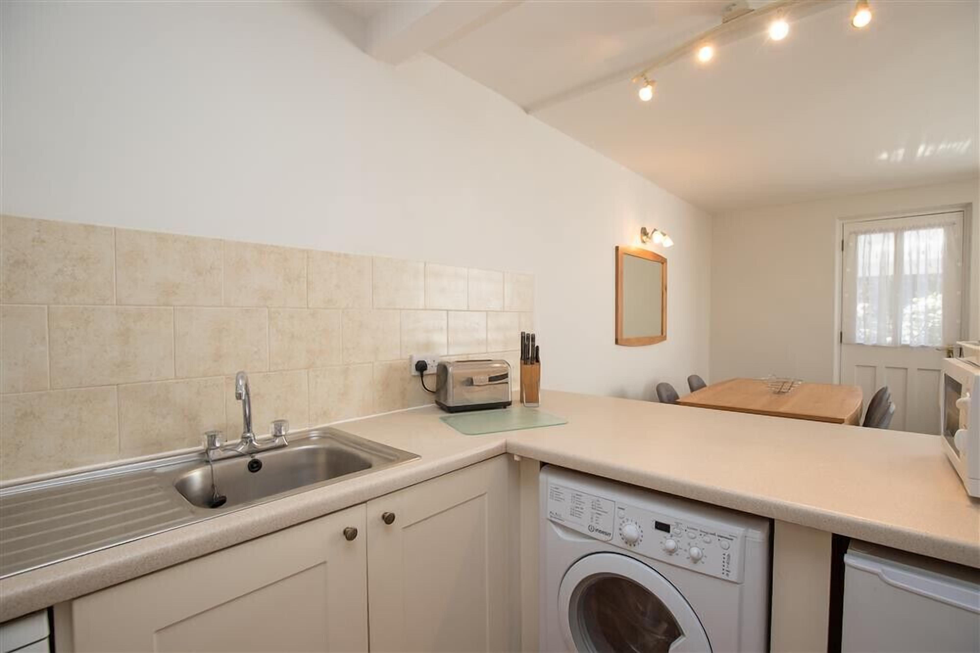 A compact kitchen with a built-in washing machine, a sink, and a toaster.