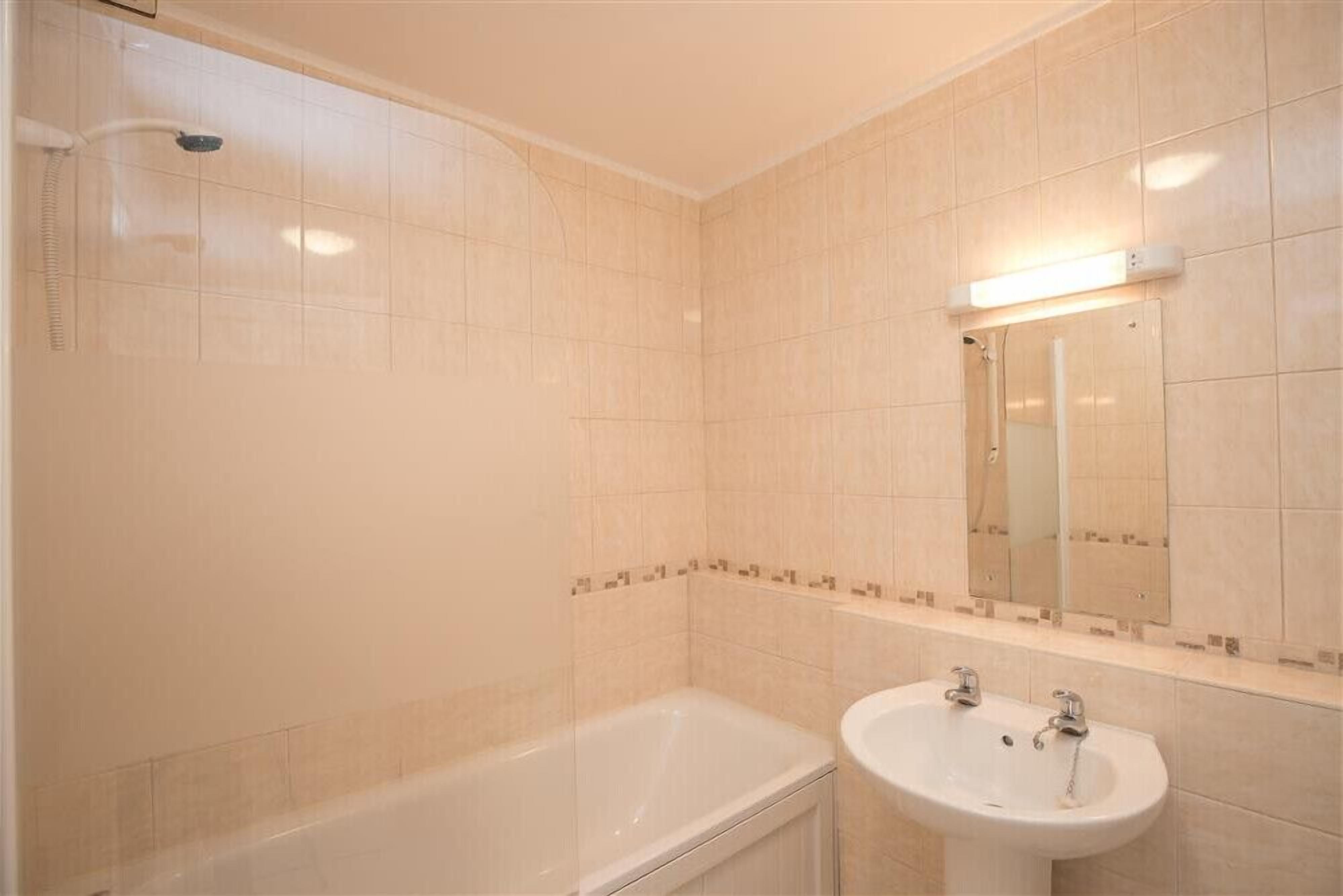 A bathroom with a bathtub, a sink, and a mirror.