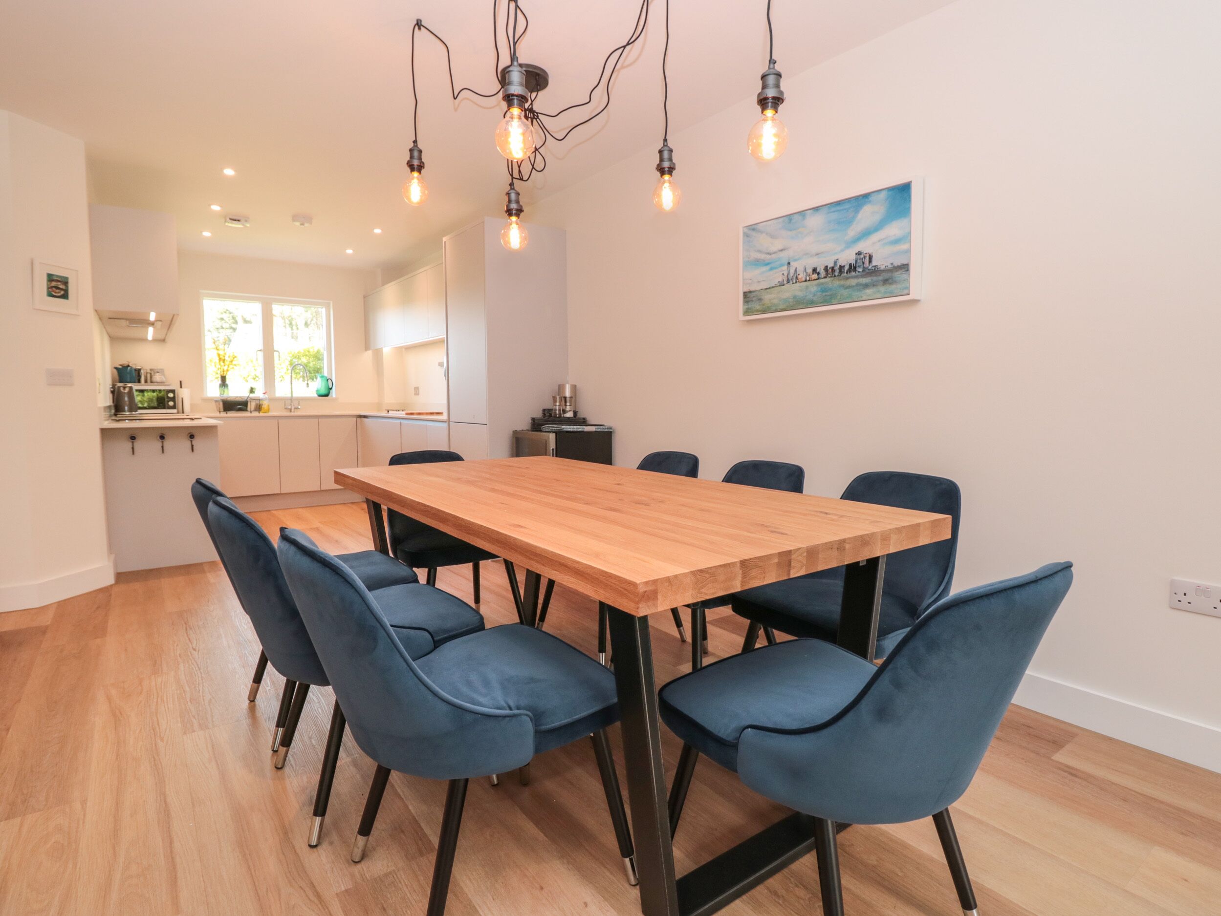 A modern kitchen with white cabinets, a wooden dining table, and blue chairs.