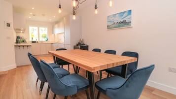 A modern kitchen with white cabinets, a wooden dining table, and blue chairs.