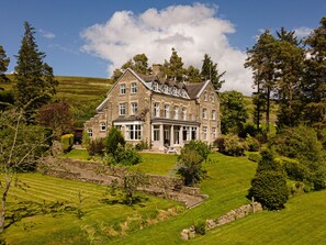 A large stone house with multiple windows and a well-maintained lawn.
