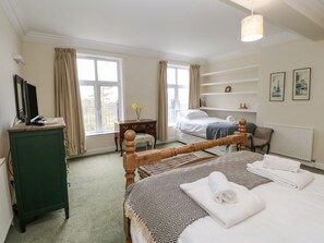 A bedroom with a bed, a dresser, a desk, and a window.