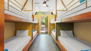 Ein Korridor mit Stockbetten, Holzgeländern und einem Deckenventilator.
