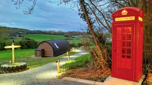 A red telephone booth, a wooden structure with a sloped roof, and a directional signpost in a rural setting. - Lakeview Lodge- UK40692 (Crowhurst)