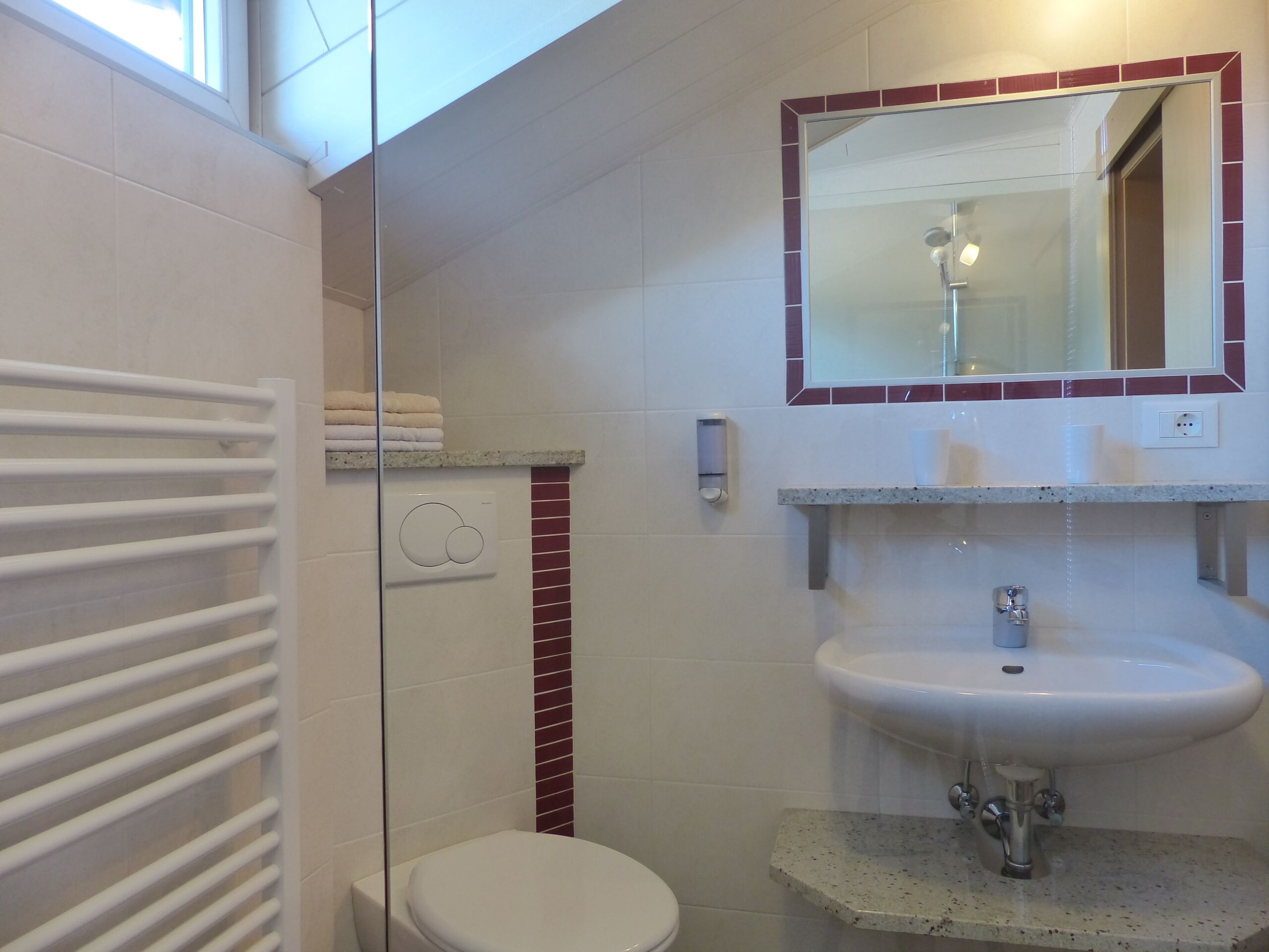 Une salle de bain comprenant des toilettes, un lavabo, une douche en verre et un porte-serviettes.