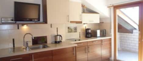 A modern kitchen with wooden cabinets, a built-in microwave, and a coffee maker.