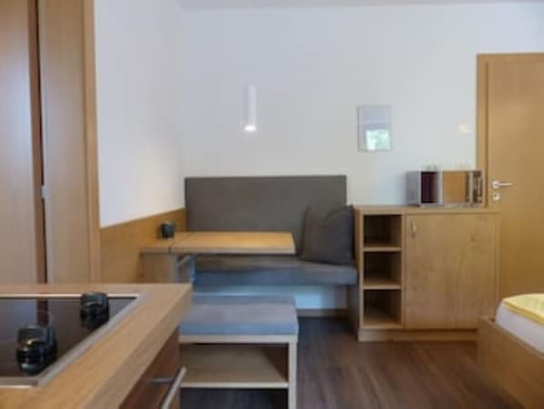 Une pièce de taille modeste comprenant un lit, un petit bureau et une banquette intégrée.