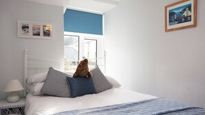 Une chambre à coucher avec un lit, des oreillers, une table de chevet, une lampe et une fenêtre donnant sur un beau paysage.