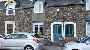 A stone building with a traditional design, featuring a prominent chimney, multiple windows, and a green door. - 3 bedroom accommodation in Keswick (Keswick)