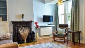 A living room with a fireplace, a television, a sofa, and a patterned rug. - 3 bedroom accommodation in Keswick (Keswick)
