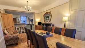 Un comedor con una larga mesa de madera, sillas tapizadas de color negro y un candelabro.