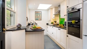 A modern kitchen with a central island, white cabinetry, a Bosch oven, and a motivational poster on the wall. - Greystones (Windermere)
